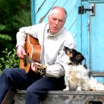 Singer, songwriter and author Terence Blacker with his guitar and his dog looking like they're singing together